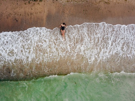 Young asian woman on the beach on the sand near the waves.の写真素材