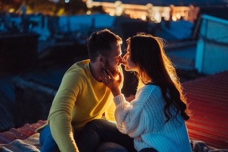 Loving couple is sitting on the roof of the house.の写真素材
