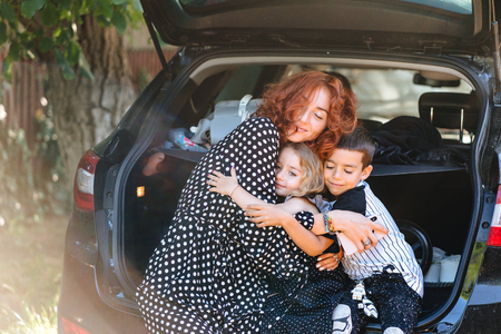 Happy woman sitting with her children in the carの写真素材