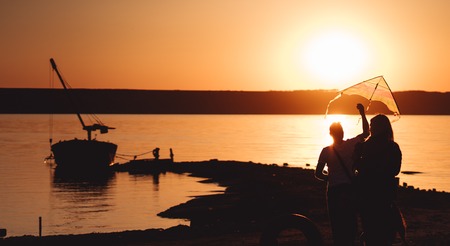 A young couple on the shore launches a kiteの写真素材