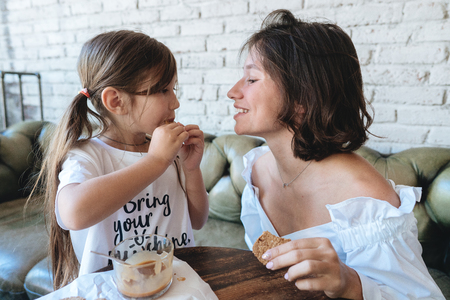 girl with her mother eats oatmeal cookies and have funの写真素材