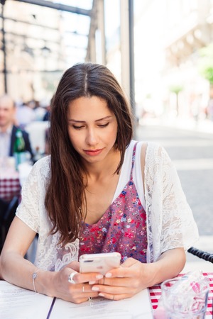 Attractive woman in a street cafe with a phone.の写真素材