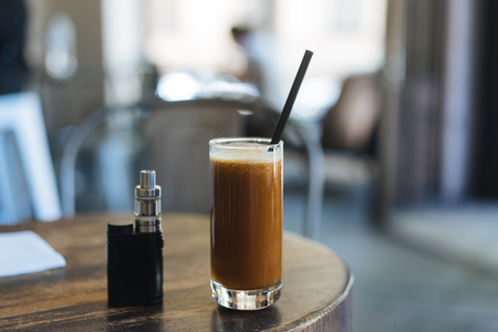 Cocktail glass and an electronic cigarette are on the tableの写真素材