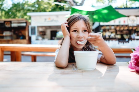 Little girl eating ice cream at a cafeの写真素材