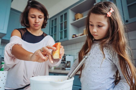 mom teaches her little daughter to cook foodの写真素材