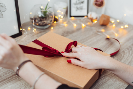 Woman wrapping present in paper with red ribbon.の写真素材