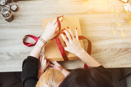 Woman wrapping present in paper with red ribbon.の写真素材