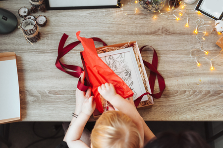 Woman wrapping present in paper with red ribbon.の写真素材