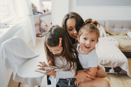 Mom and two daughters are looking at the smartphoneの写真素材