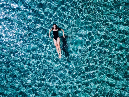 Young girl in a black swimsuit swims in the sea.の写真素材