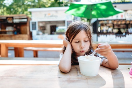 Little girl eating ice cream at a cafeの写真素材