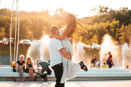 Handsome guy twists a beautiful girl on a background of a fountainの写真素材