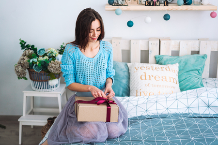 Girl sitting in bed with present boxの写真素材