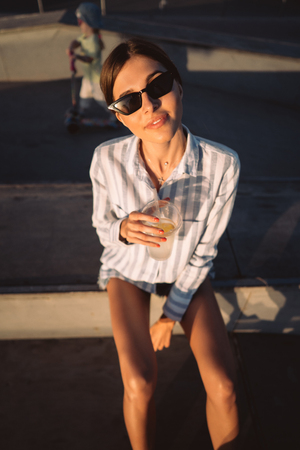 Young girl in sunglasses with a glass of lemonade.の写真素材