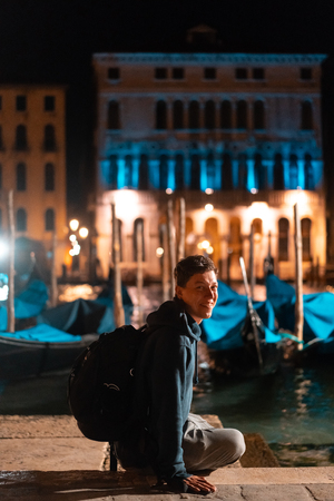 Young handsome guy walks alone by venice at nightの写真素材