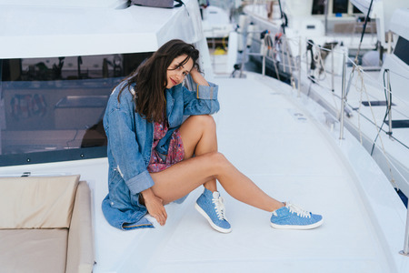 Young beautiful girl is sitting on the deck of a yachtの写真素材