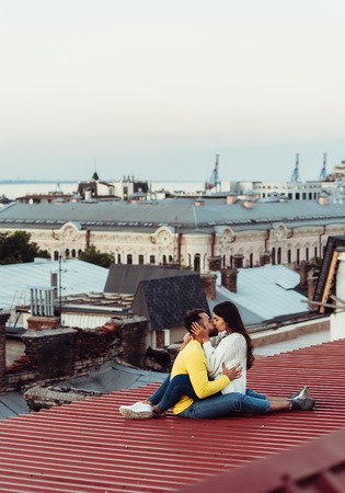 Loving young couple is sitting on the roof of the house.の写真素材