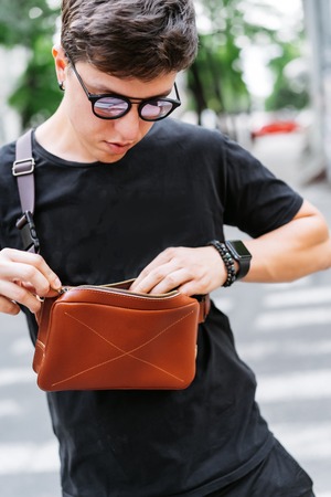 Guy looking for something in his bag.の写真素材