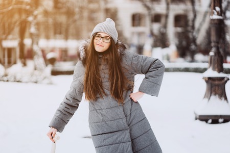 Beautiful girl in winter fashion clothes with a shovelの写真素材