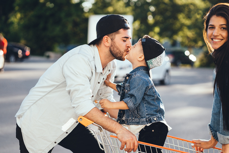 Young parents put their son in a cart and have fun in the parking.の写真素材
