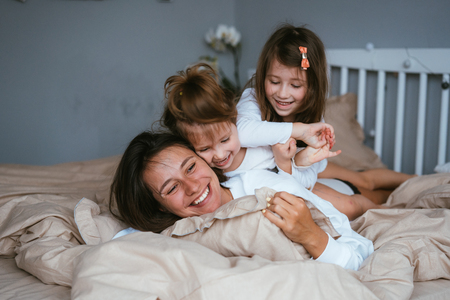 Mom and her two little cute daughters are having funの写真素材