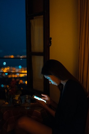 Woman using smart phone for online at home in eveningの写真素材