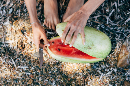 Close-up of a young beautiful woman cuts watermelonの写真素材