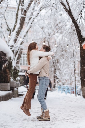 young guy holds a beautiful girl in his arms. Couple in sweaters.の写真素材