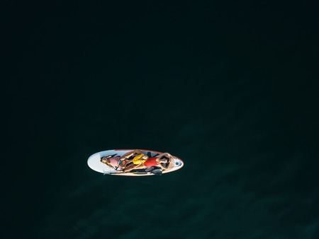 Mother with two daughters stand up on a paddle boardの写真素材