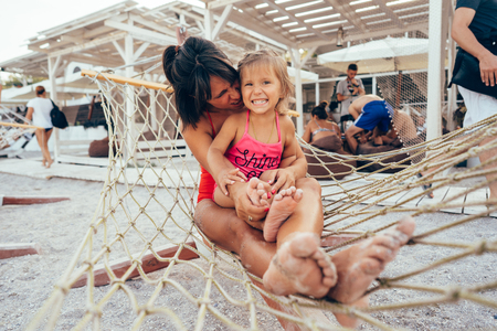 happy mother with her daughter lying in a hammockの写真素材