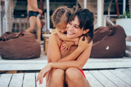 Young mother giving daughter piggyback ride on the beachの写真素材
