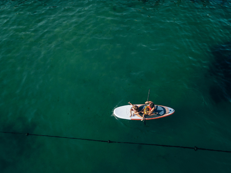 Mother with two daughters stand up on a paddle boardの写真素材