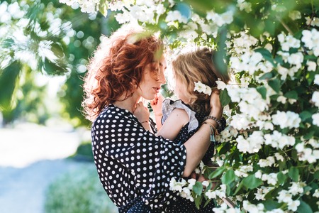 Young woman stands near jasmine with a small daughterの写真素材