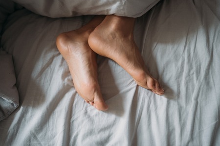 Close-up woman feet alone in white bed