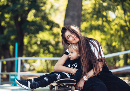 Beautiful young hipster mom and little son at the skateparkの写真素材