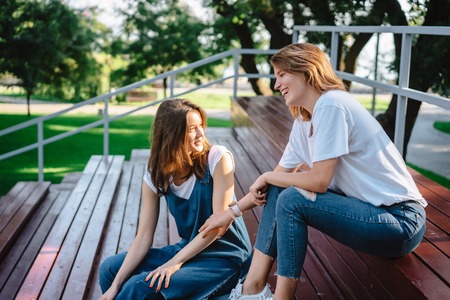 Two beautiful young woman resting on a benchの写真素材