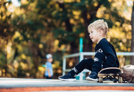 Young kid sitting in the park on a skateboard.の写真素材
