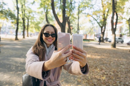 Beautiful young girl holds in her hands two smartphonesの写真素材