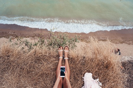beautiful young girl sitting and holding a smartphone in her hands, top view