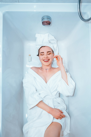 Relaxed woman with towel on hair lying in bathtub