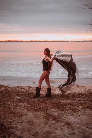 Beautiful young girl in a swimsuit on the shore of a frozen lake