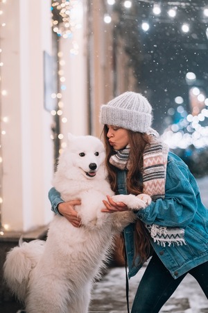 A woman is hugging her dog on a night street.の写真素材
