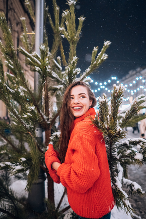 Young woman posing near the Christmas tree on the streetの写真素材