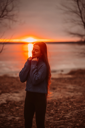 Woman enjoying time relaxing by the beautiful lake at sunrise.の写真素材