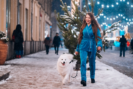 Woman walking down with white dog by alley.の写真素材