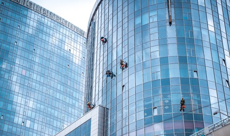 Several workers washing windows in the office building