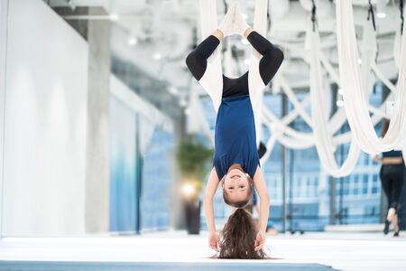 portrait of a beautiful young girl engaged in fly yoga on canvases.の写真素材