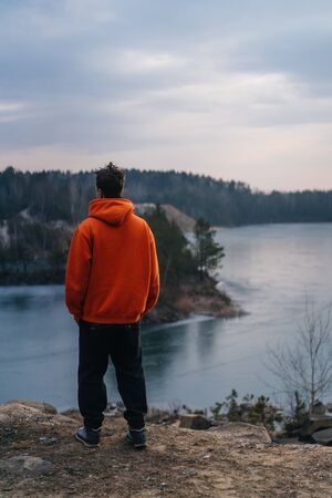 A young man standing on the edge of a cliff poses for the cameraの写真素材