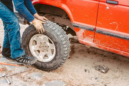Man rolls a new replacement wheel to 4x4 off road truckの写真素材