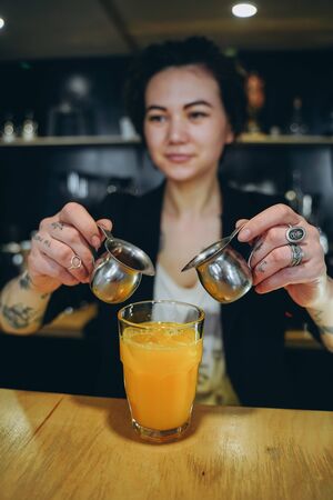 KIEV, UKRAINE - APRIL 14, 2019 A girl makes a orange coffee cocktailのeditorial素材